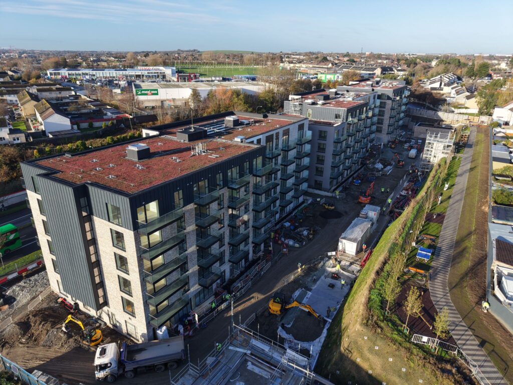A photo looking down on three apartment buildings.They are all 6 stroies high and have a red roof. There is construction work happening outside the apartment blocks.