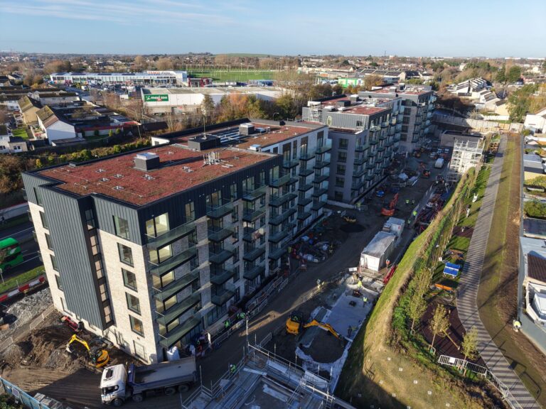 A photo looking down on three apartment buildings.They are all 6 stroies high and have a red roof. There is construction work happening outside the apartment blocks.