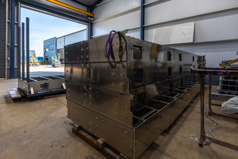 A large metal structure with purple strap handles on it.It is in a large corragated metal shed.