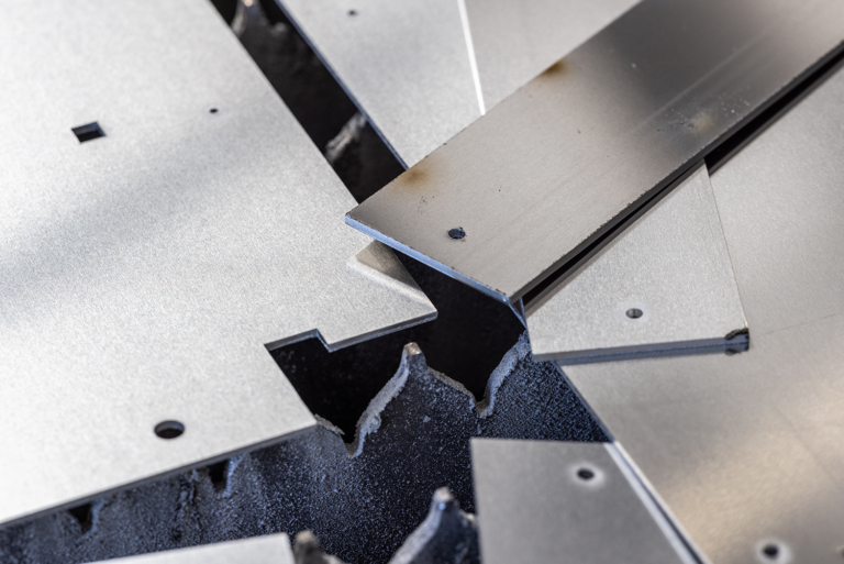 multiple thick grey industrial metal plates overlapping on a dark textured surface