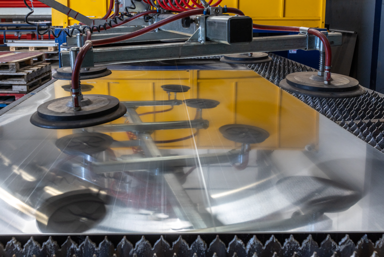 A large sheet of metal in a machineThere is circular machinery above it.