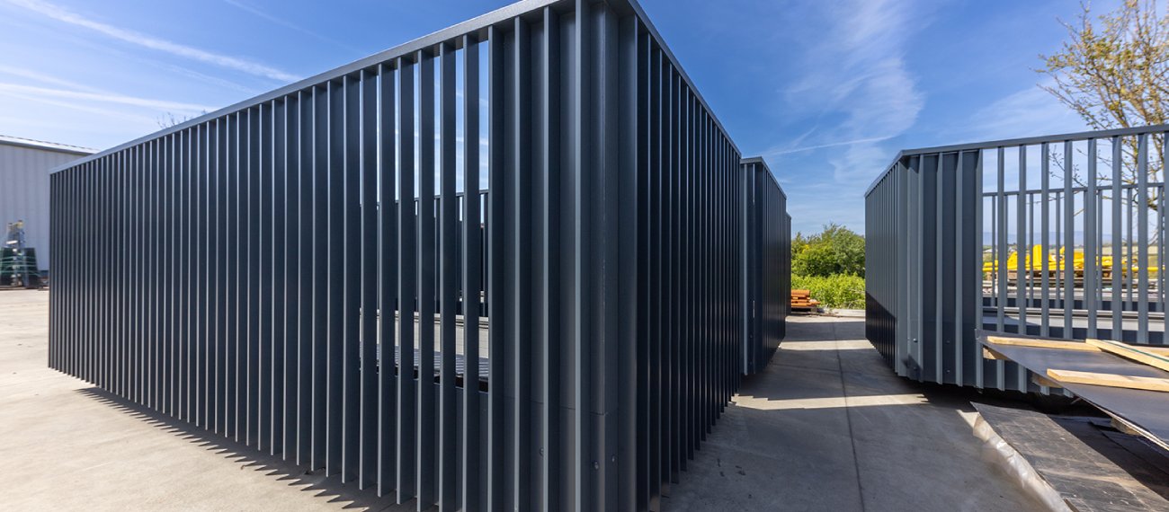 Multiple large dark grey structures it has a fence like pattern in the middle . The structure has 3 sides and 1 open side and a dark grey bottom